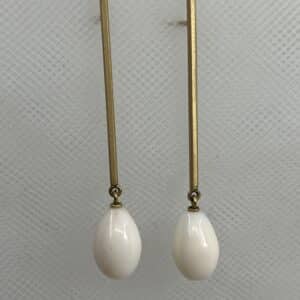 Pendientes largos de oro amarillo matizado y gotas de coral natural blanco.