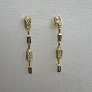 Pendientes largos de plata chapados en oro amarillo con circonitas lilas y blancas.