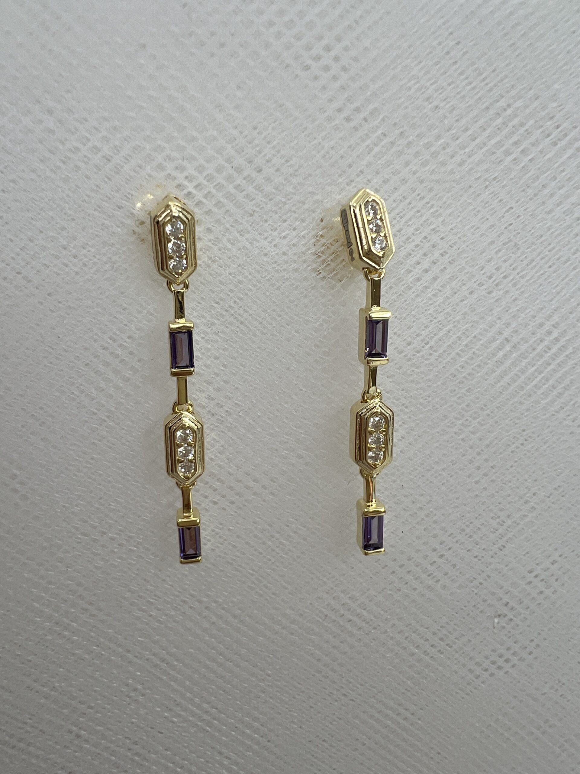 Pendientes largos de plata chapados en oro amarillo con circonitas lilas y blancas.