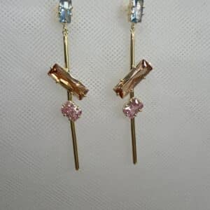 Pendientes largos de plata chapados en oro amarillo con circonitas de colores azul ambar y rosa.