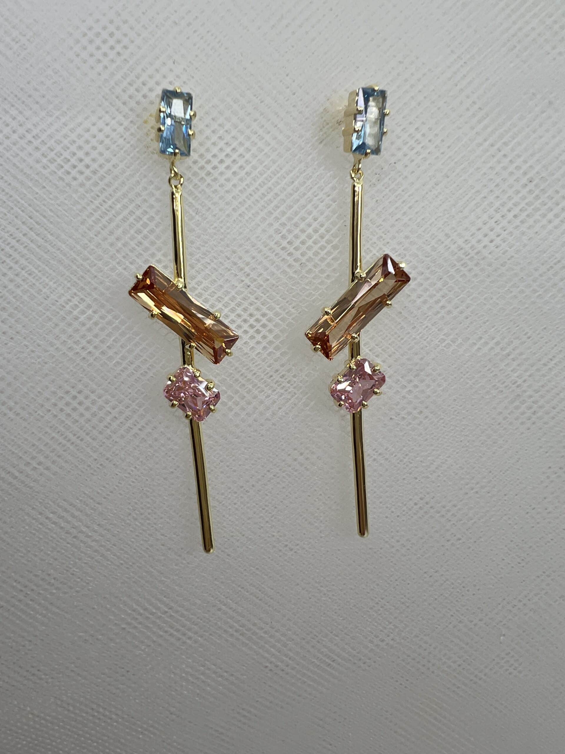 Pendientes largos de plata chapados en oro amarillo con circonitas de colores azul ambar y rosa.