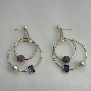 Pendientes largos de plata chapados en oro amarillo con perlas y piedras naturales y circonitas de color morado.