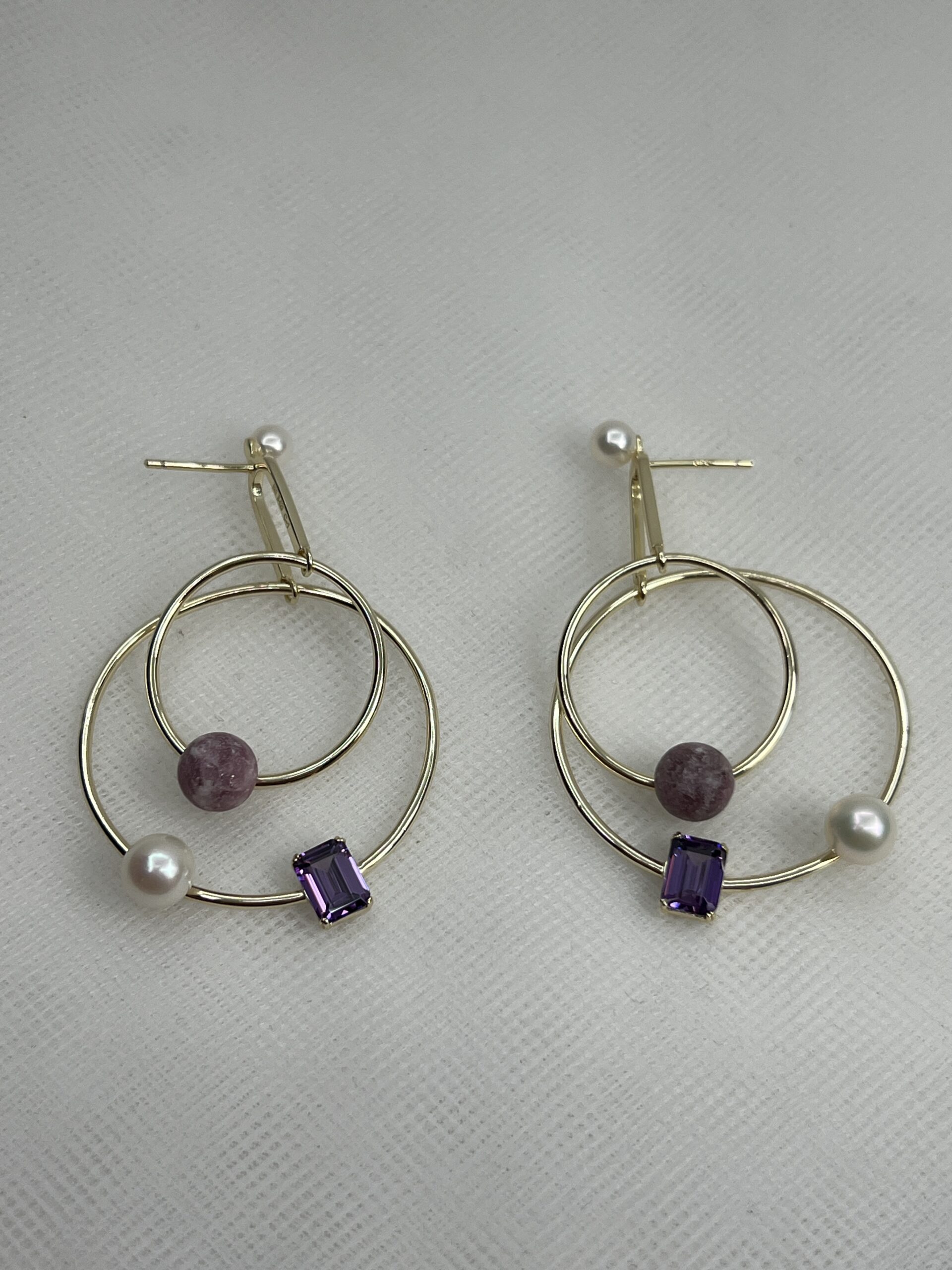 Pendientes largos de plata chapados en oro amarillo con perlas y piedras naturales y circonitas de color morado.