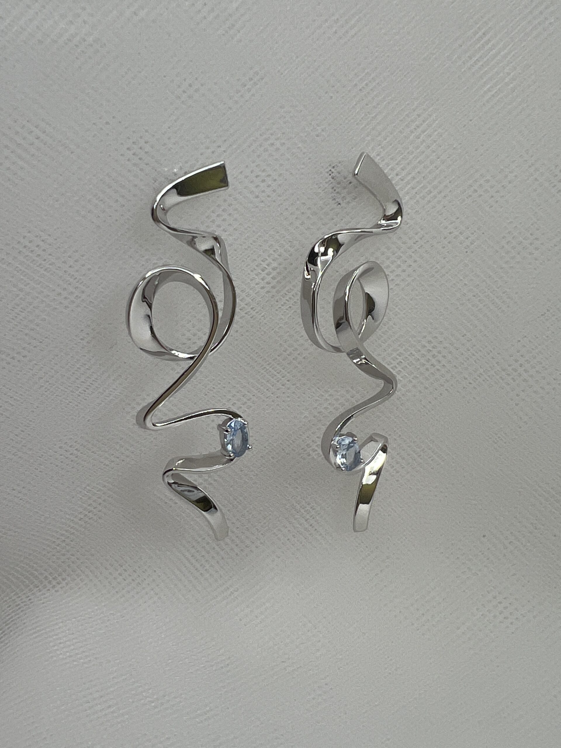 Pendientes largos de plata rodiados en oro blanco con circonita de color azul.
