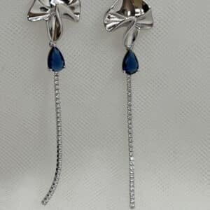 Pendientes largos de plata rodiados en oro blanco boton con formas onduladas y cadena de circonitas con piedra azul.