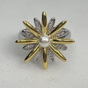 Anillo de plata rodiado en oro blanco y chapado en oro amarillo con forma de flor adornado con perla natural y circonitas.