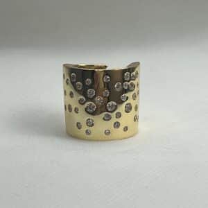 Anillo XL de plata  chapado en oro amarillo brazo ancho ajustable con circonitas engastadas de distintos tamaños.