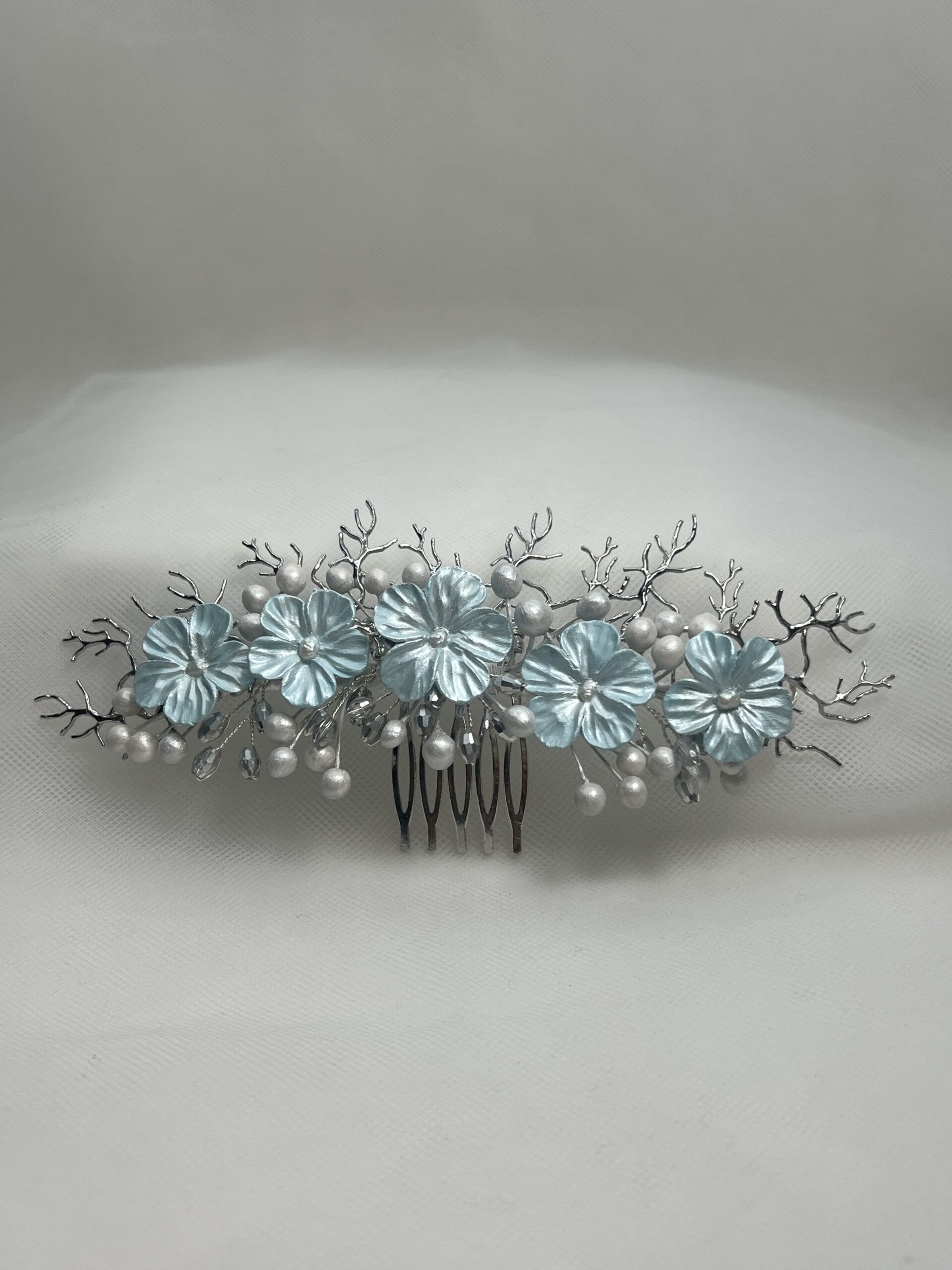 Tocado de flores de porcelana y ramitas de metal plateado.